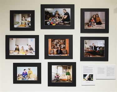 Selection of 8 photographs on the museum wall displaying Uyghur people in their homes