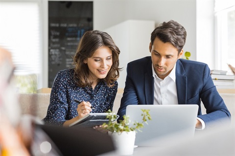 Business woman and business man working together while looking at a laptop screen