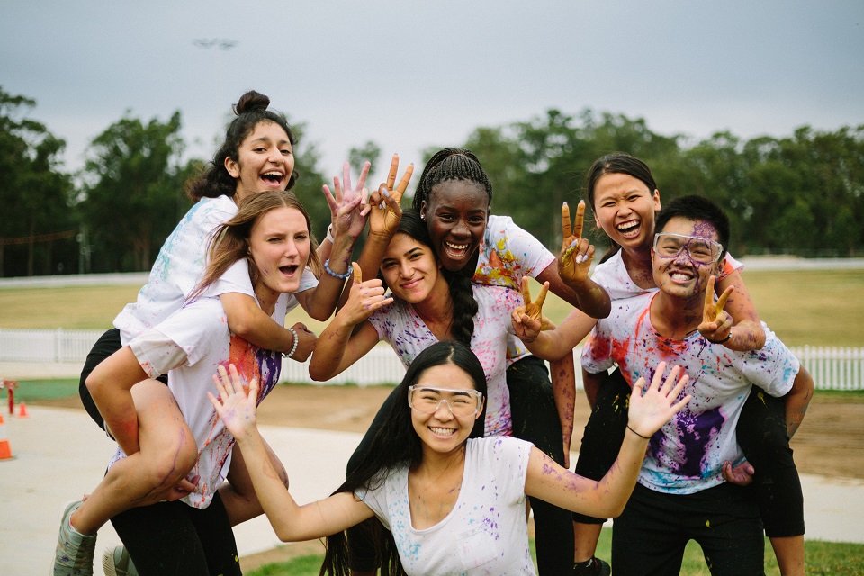 Group of young people posing while covered in colourful paint 