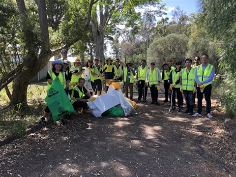 Fairfield City Council staff members wearing high visibility vest, smiling and posing, while holding garbage bags and grabbers 