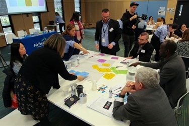 Group of seven people participating in a group activity around at table at the Fairfield Conversations summit