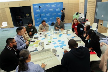 Group of people participating in a group activity around at table at the Fairfield Conversations summit