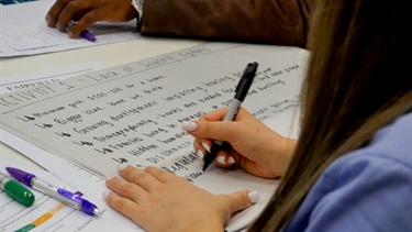 Woman writing key points on a piece of paper, relating to a group activity about the lack of housing options available to some residents