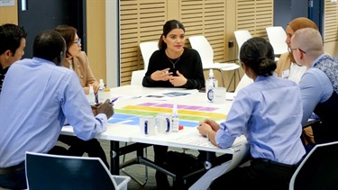 Woman expressing her views on topic as six other people seated around the same table listen intently as part of a Fairfield Conversations summit group activity