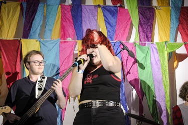 Local band, Midnight Dreamers, performing in front of wall of colourful flags at Fairfield Youth Centre. Photographed by Jennifer, Tyna & Jacintha
