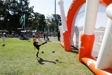 Young boy kicking ball into inflatable goal posts