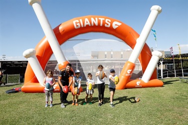 Young children with instructor posing with footballs