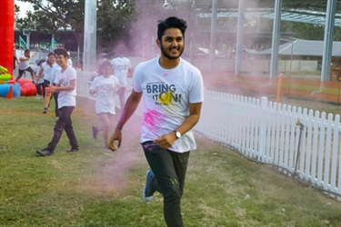 Young man running through pink colour powder