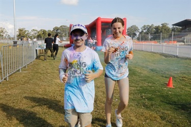 Young boy and girl covered in blue, orange and purple colour powder