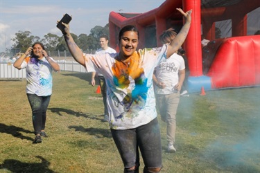 Young girl posing while covered in orange and blue colour powder