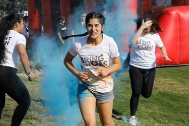 Young girl running past a cloud of blue colour powder