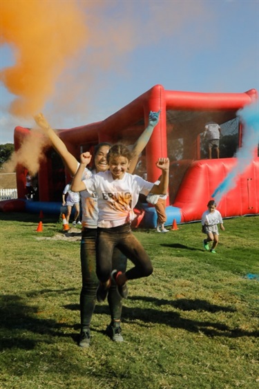 Young girls posing and smiling in clouds of orange and blue colour powder