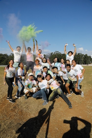 Group of young people posing and smiling covered in colourful colour powder