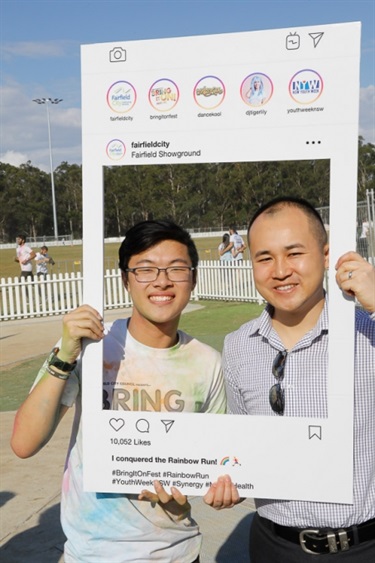 Young man smiling and posing with Councillor Adrian Wong while holding Instagram frame prop
