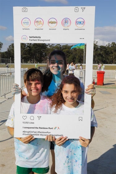 Three young friends posing with Instagram frame prop