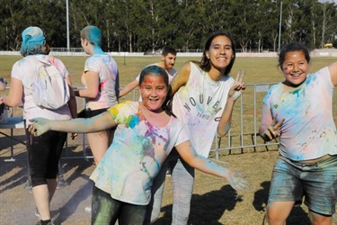 Group of young girls covered in colourful colour powder smiling and posing