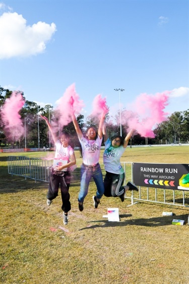 Young girls jumping into the air and throwing pink colour powder