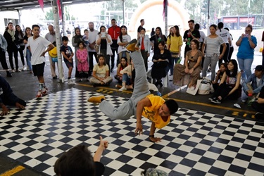 Festival go-ers watching young boy break dancing on dance floor