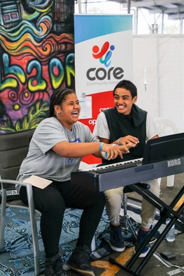 Young girl and boy laughing and playing on keyboard