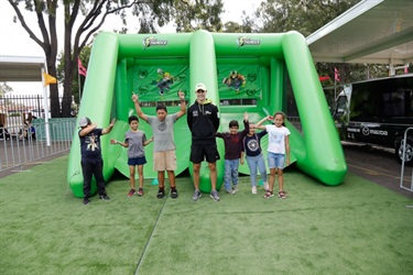 Young children with instructor posing in front of inflatable ball toss game