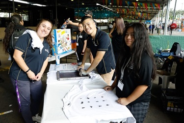 Stallholders smiling and screen printing shirts
