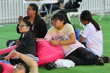 Young friends sitting on colourful bean bags on artificial grass