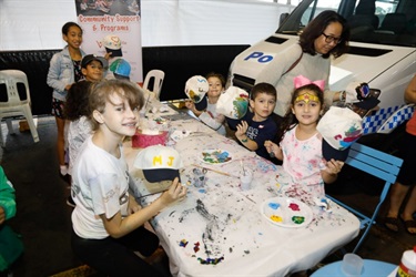 Young children sitting at a table and painting baseball caps with colourful paint