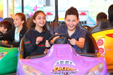 Young girl and boy smiling in a purple bumper car
