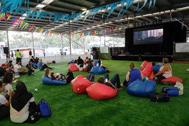 Families sitting on pink and blue bean bags watching a movie