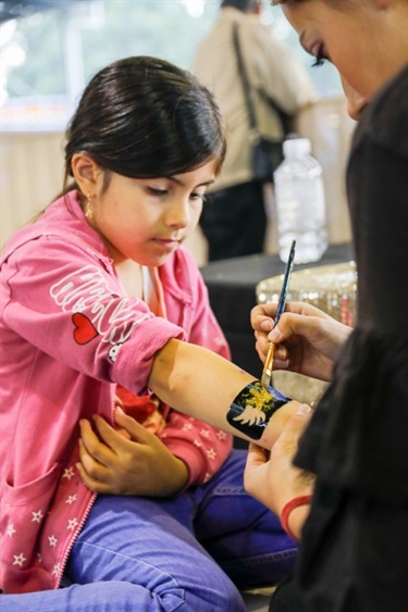 Young girl receiving gold glittery painte tattoo