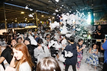 Foam coming down on young people dancing on the dance floor