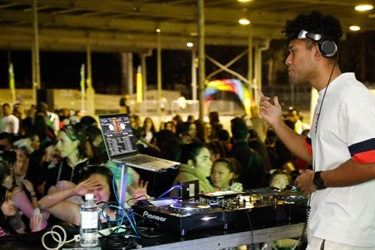 DJ at the turntables in front of a crowd of young people on the dance floor
