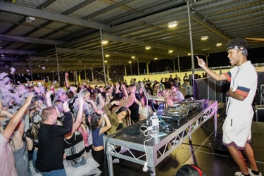 DJ looking at crowd of young people covered in foam and dancing