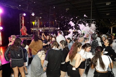 DJ Tiger Lily performing for crowd of young people covered in foam on the dance floor