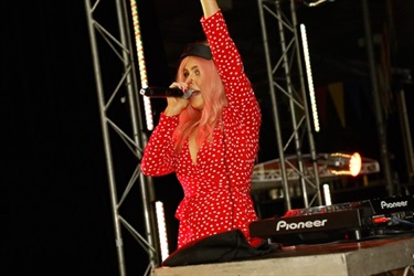 DJ Tiger Lily speaking into a microphone with her arm raised