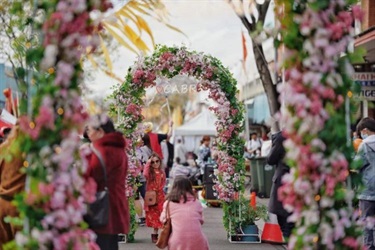 Woman photographing child beneath floral arches