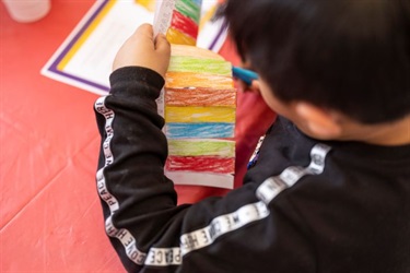 A young boy colouring in a paper lantern