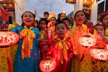 Young girls and boys dressed in Vietnamese traditional costumes holding lit up lanterns
