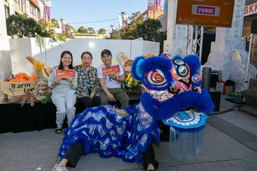 Angie Hong and competition winners seating in front of cooking stage with a blue lion