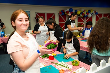 Young girl smiling and posing with bowl of tabouli at the kid's cooking workshop