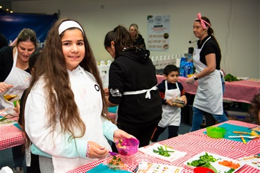 Young girl smiling and posing while combining ingredients in a bowl at the kid's cooking workshop