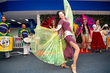Young woman wearing traditional cultural dress performing alongside drummers and Brazilian dancers