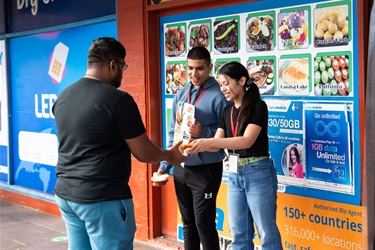 Two volunteers handing out free curry samples to a young man