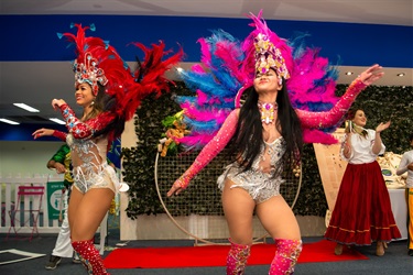 Brazilian dancers wearing red and pink sparkly costumes smiling and dancing