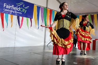 Two young women in red, black and gold costumes performing Spanish dance