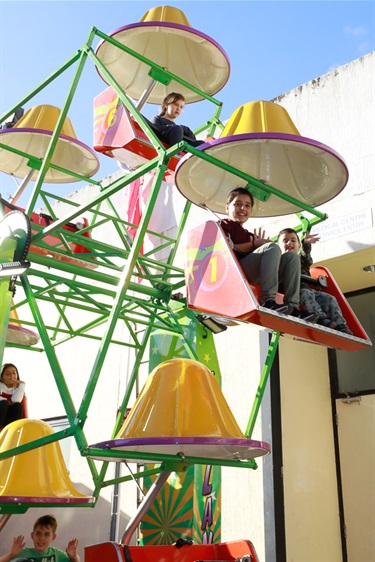 Young children smiling while riding on small ferris wheel