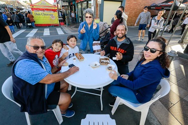 Family smiling and sitting around table while eating churros