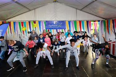 Group of dancers in street wear demonstrating their dance moves to young children