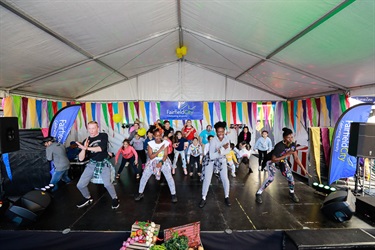 Group of dancers in street wear demonstrating their dance moves to young children
