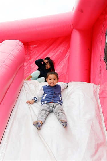 Two young children sliding down jumping castle slide